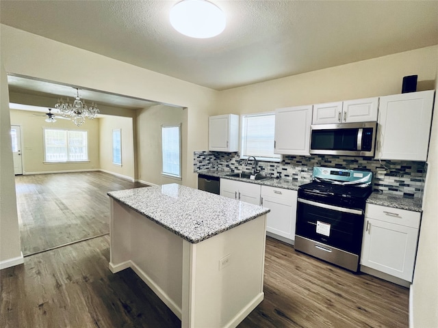 kitchen featuring white cabinetry, appliances with stainless steel finishes, decorative light fixtures, and sink