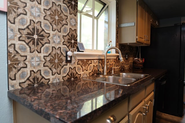 kitchen featuring dishwasher, tasteful backsplash, dark stone counters, and sink