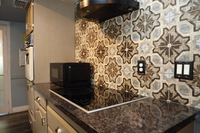 kitchen featuring black appliances, extractor fan, dark wood-type flooring, and dark stone counters