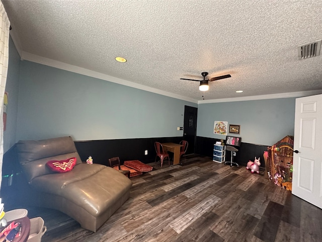 recreation room featuring dark hardwood / wood-style flooring, a textured ceiling, ceiling fan, and crown molding