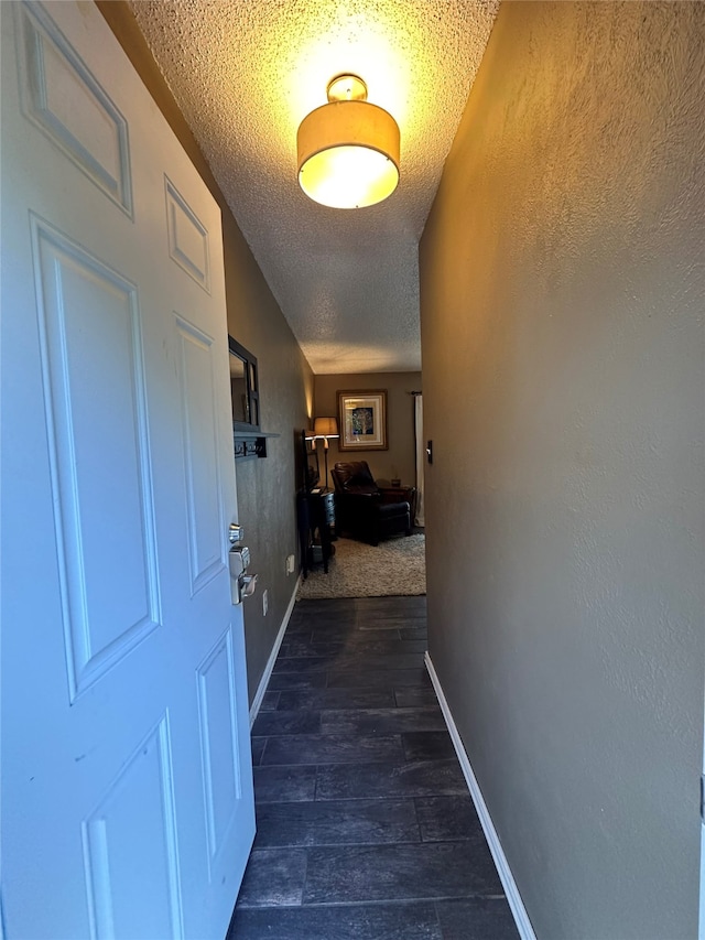 corridor with dark hardwood / wood-style floors and a textured ceiling