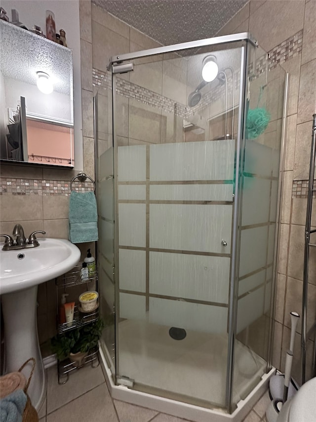 bathroom featuring a textured ceiling, tile patterned floors, tile walls, and a shower with shower door