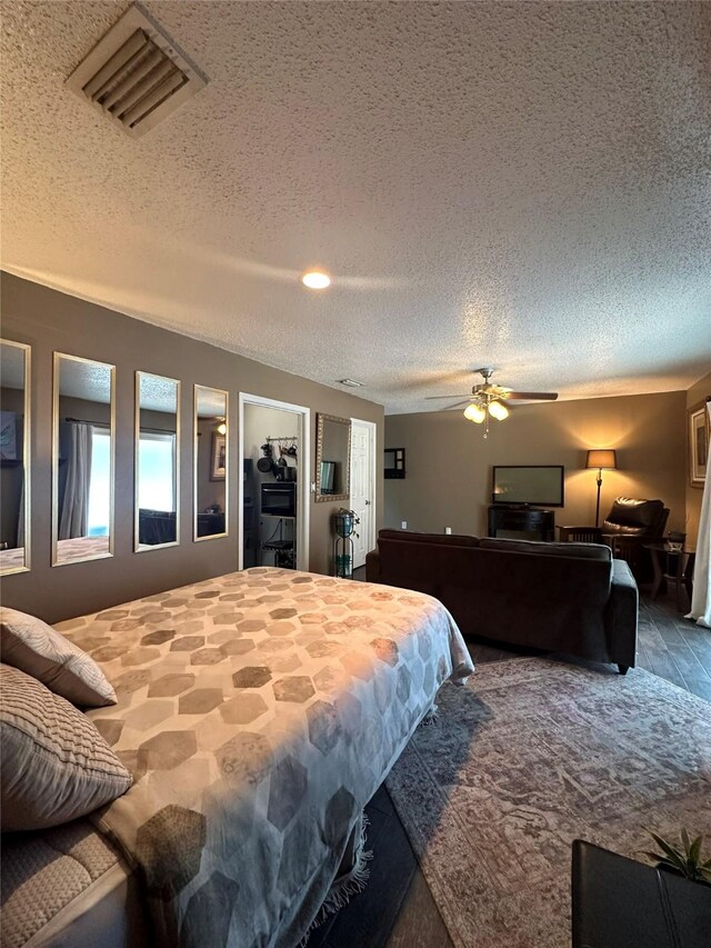 bedroom featuring a textured ceiling, ceiling fan, wood-type flooring, a spacious closet, and a closet