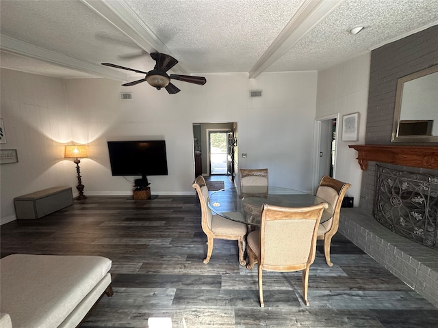 dining room featuring a textured ceiling, ceiling fan, dark wood-type flooring, and a brick fireplace