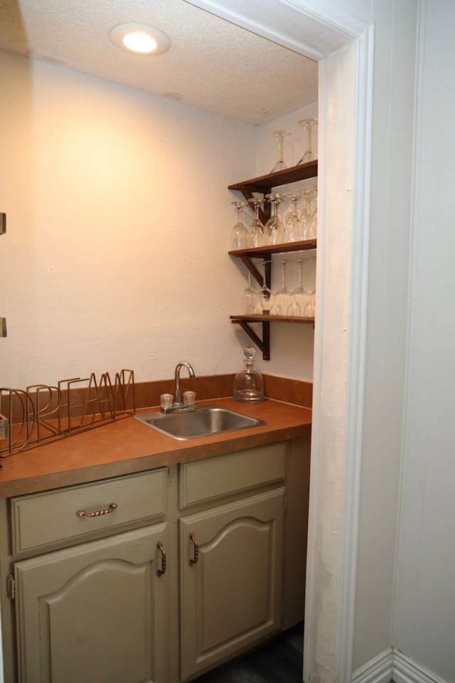 bar featuring a textured ceiling and sink