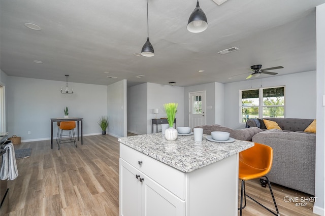 kitchen featuring a center island, hanging light fixtures, light hardwood / wood-style flooring, white cabinets, and ceiling fan with notable chandelier