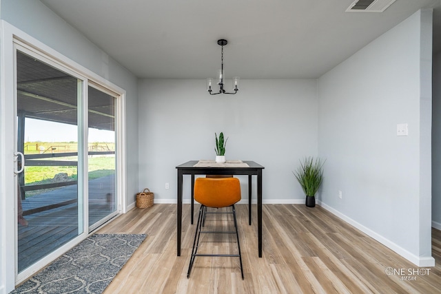 dining area with light hardwood / wood-style floors and a notable chandelier