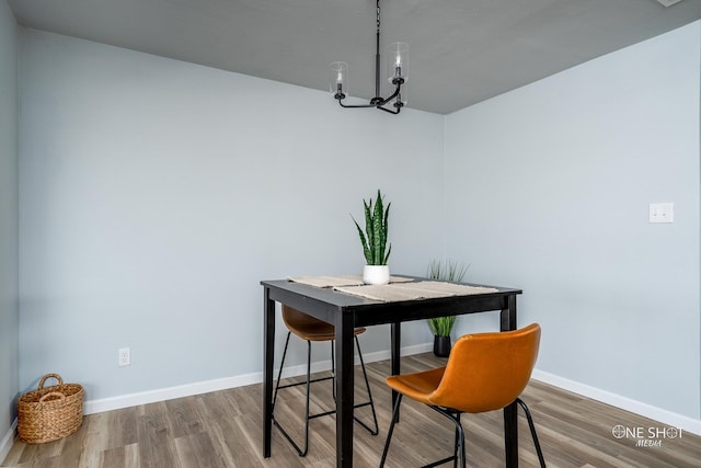 dining space with hardwood / wood-style floors and a notable chandelier