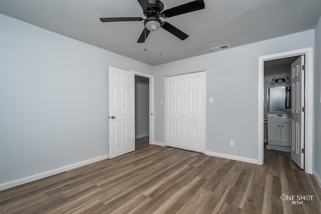 unfurnished bedroom with a closet, connected bathroom, dark hardwood / wood-style floors, and ceiling fan