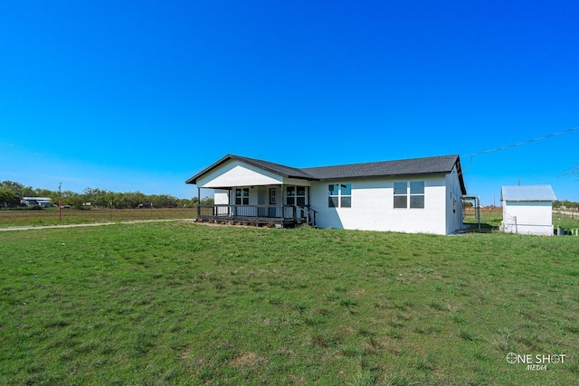 rear view of property with covered porch and a yard