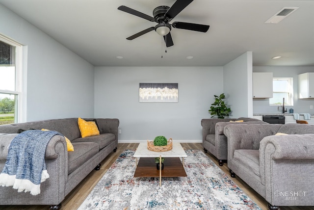 living room with light hardwood / wood-style flooring, ceiling fan, and sink