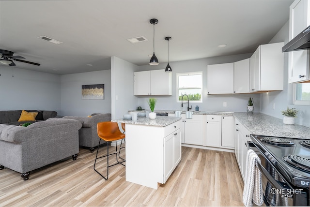 kitchen featuring white cabinetry, a center island, light stone countertops, decorative light fixtures, and a kitchen bar