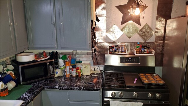 kitchen featuring gray cabinetry, dark stone countertops, and appliances with stainless steel finishes