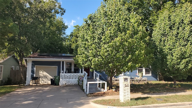 view of property hidden behind natural elements featuring a garage and covered porch