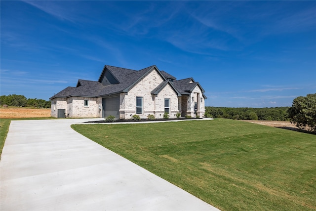 french country style house featuring a garage, a front lawn, and central AC