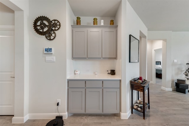 bar featuring gray cabinetry, light wood-type flooring, and backsplash