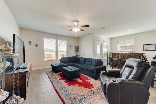 living room featuring ceiling fan, bar area, and light hardwood / wood-style flooring