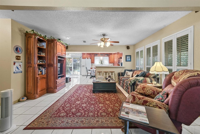 living room featuring ceiling fan, light tile patterned flooring, and a textured ceiling