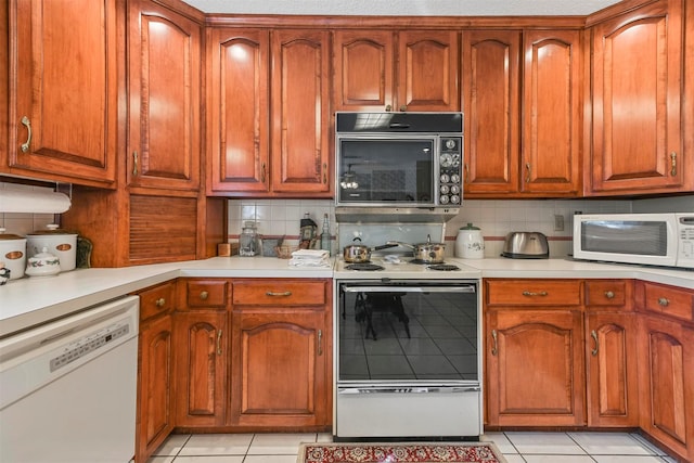 kitchen with white appliances, backsplash, and light tile patterned floors