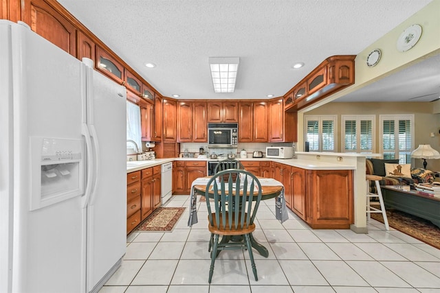 kitchen with light tile patterned floors, white appliances, and a textured ceiling