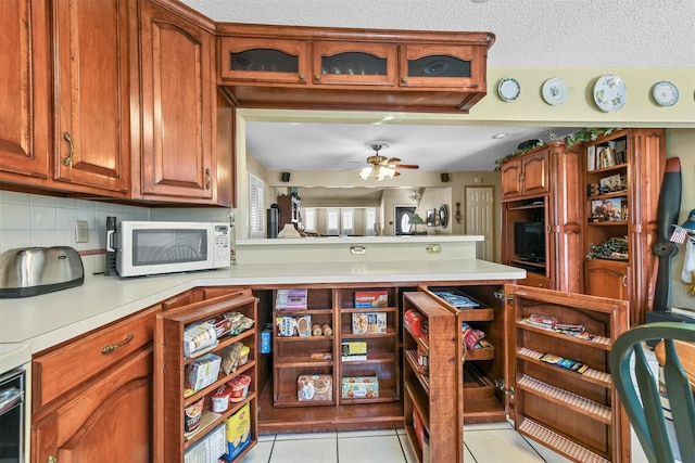 kitchen with ceiling fan, decorative backsplash, light tile patterned floors, a textured ceiling, and kitchen peninsula