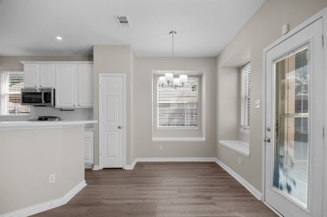 kitchen with white cabinets, hanging light fixtures, a chandelier, and light hardwood / wood-style floors