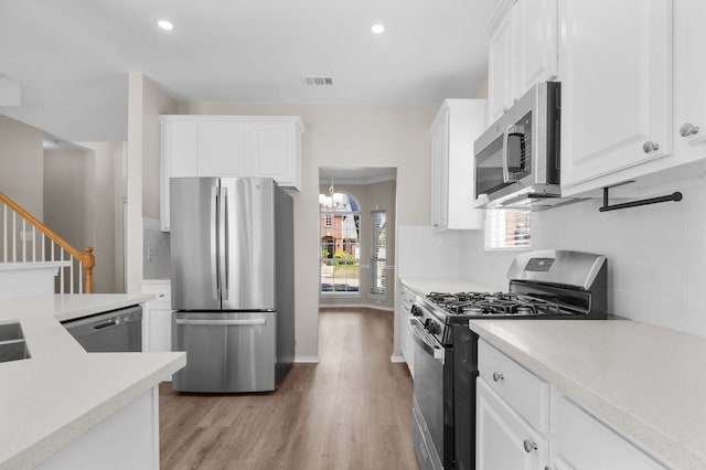 kitchen featuring decorative backsplash, light hardwood / wood-style floors, white cabinets, stainless steel appliances, and a notable chandelier