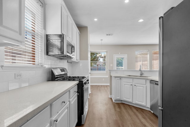 kitchen featuring light wood-type flooring, sink, stainless steel appliances, and white cabinets