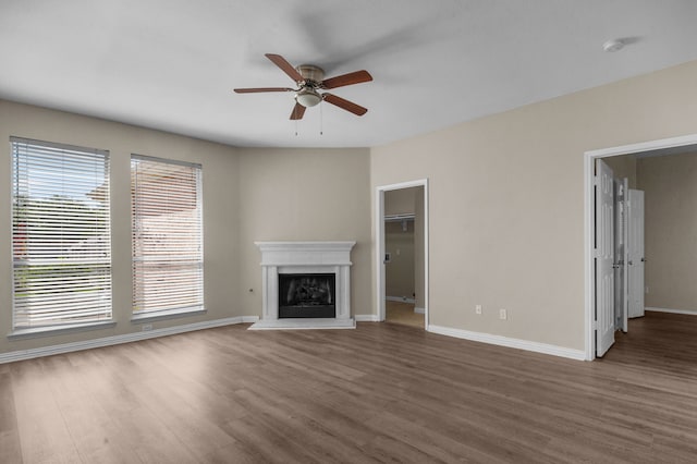 unfurnished living room featuring ceiling fan and dark hardwood / wood-style flooring