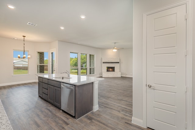 kitchen with dishwasher, light stone counters, ceiling fan with notable chandelier, hanging light fixtures, and a stone fireplace