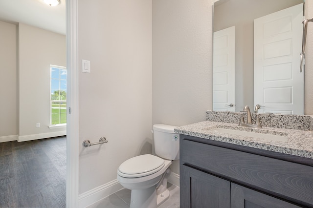 bathroom with wood-type flooring, vanity, and toilet