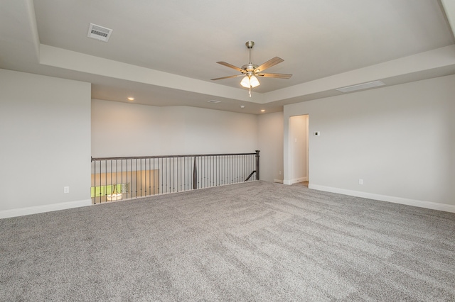 spare room with ceiling fan, carpet floors, and a tray ceiling