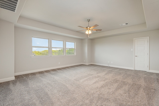 carpeted spare room with ceiling fan and a raised ceiling