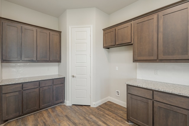 kitchen featuring light stone countertops, dark hardwood / wood-style floors, and dark brown cabinetry