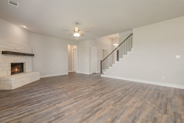 unfurnished living room featuring ceiling fan, a fireplace, and dark wood-type flooring