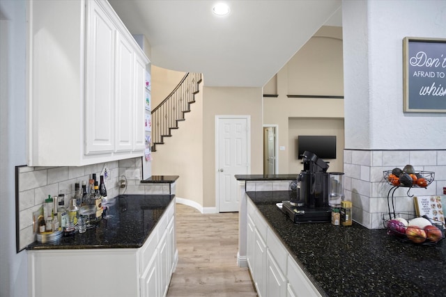 kitchen featuring tasteful backsplash, dark stone countertops, white cabinets, and light hardwood / wood-style floors