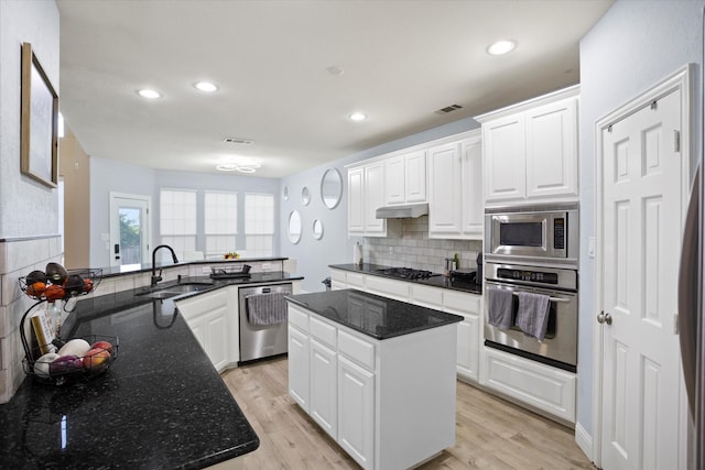 kitchen with sink, a kitchen island, light hardwood / wood-style flooring, white cabinets, and appliances with stainless steel finishes