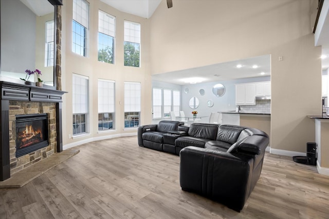 living room featuring a fireplace, light wood-type flooring, high vaulted ceiling, and a wealth of natural light