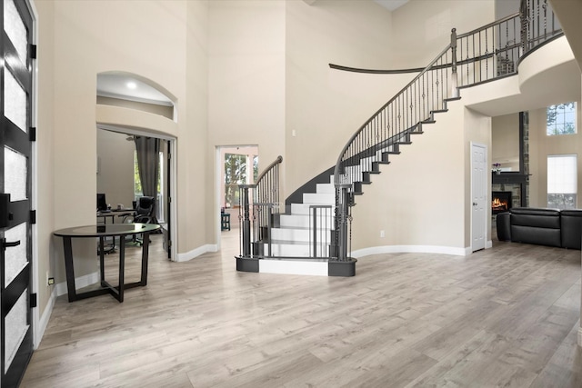 foyer featuring a healthy amount of sunlight, light wood-type flooring, and a towering ceiling