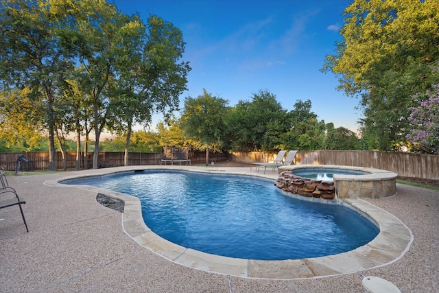 view of swimming pool featuring an in ground hot tub, a patio, and a trampoline