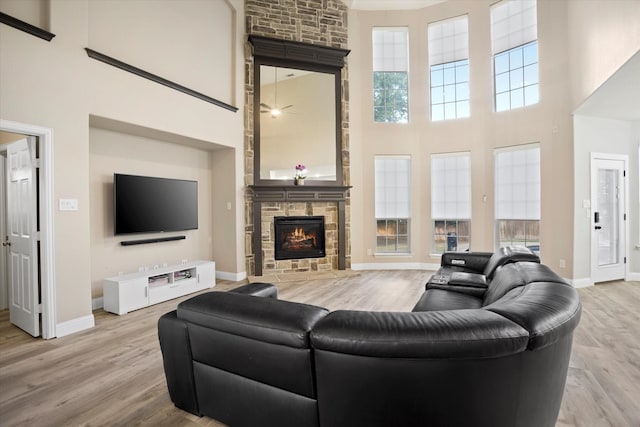 living room with a fireplace, light hardwood / wood-style flooring, and a towering ceiling