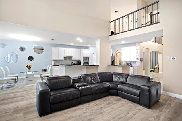 living room with a towering ceiling and light hardwood / wood-style floors