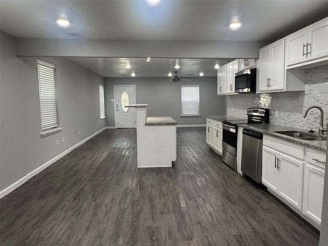 kitchen featuring appliances with stainless steel finishes, sink, white cabinetry, dark stone counters, and dark hardwood / wood-style floors