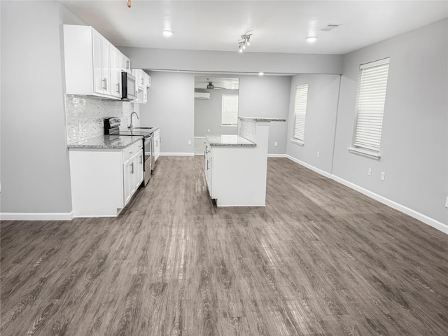 kitchen with light stone countertops, appliances with stainless steel finishes, dark hardwood / wood-style floors, and white cabinets