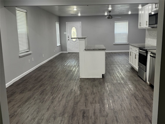 kitchen featuring white cabinetry, a healthy amount of sunlight, appliances with stainless steel finishes, and dark stone countertops