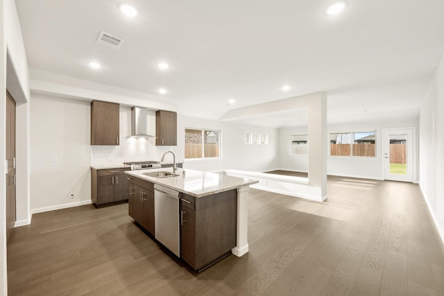 kitchen featuring plenty of natural light, dishwasher, an island with sink, and wall chimney range hood