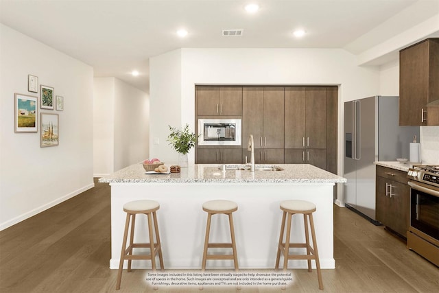 kitchen with sink, appliances with stainless steel finishes, dark hardwood / wood-style flooring, and an island with sink