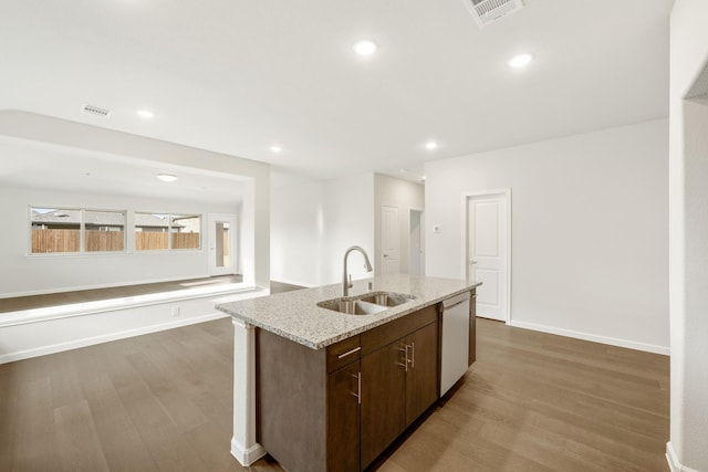 kitchen featuring sink, white dishwasher, hardwood / wood-style floors, and a center island with sink