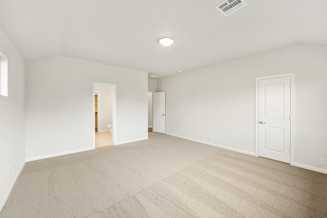 empty room featuring light colored carpet and vaulted ceiling