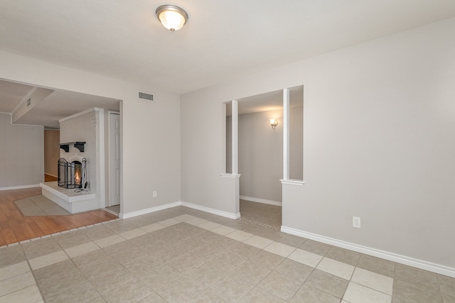 spare room featuring a multi sided fireplace and light hardwood / wood-style floors